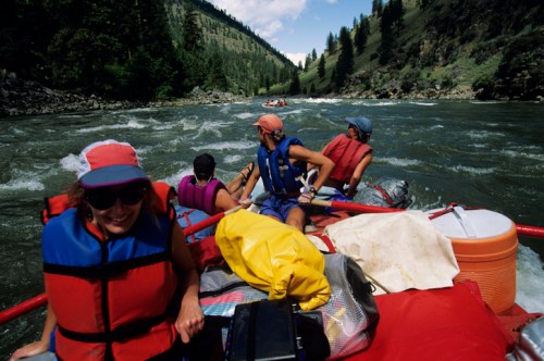 A group of people in life jackets enjoying a river rafting adventure on a scenic, rocky river.