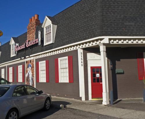 A charming restaurant exterior with red shutters, a red door, and a brick chimney, set against a clear blue sky.