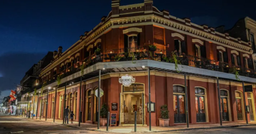 Historic building at night, featuring red brick architecture and illuminated windows, set in a lively urban street.