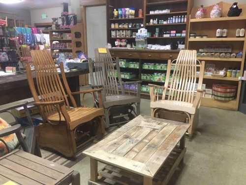 A cozy store interior featuring wooden rocking chairs and a rustic table, surrounded by shelves of various products.