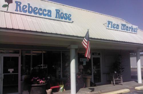 Exterior of a flea market with a sign reading "Rebecca Rose" and an American flag hanging outside.