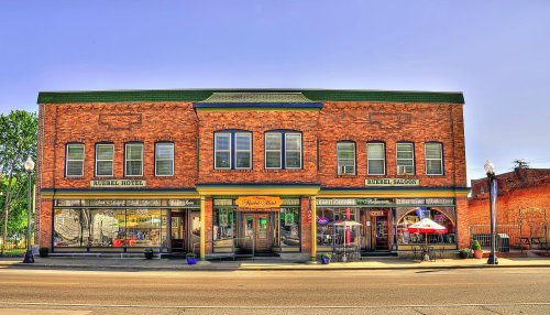Historic brick building featuring the Russell Hotel and Russell Saloon, with outdoor seating and colorful planters.