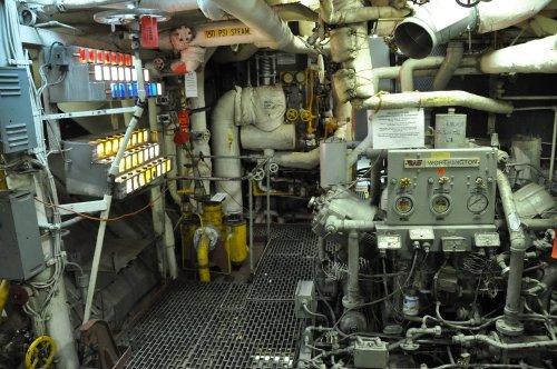 Engine room with pipes, gauges, and control panels, showcasing industrial machinery and equipment.