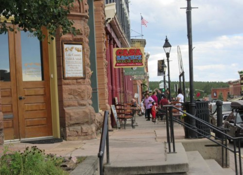 A street scene featuring a restaurant sign for "Casa Sanchez," with people walking and shops in the background.