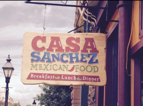 Sign for "Casa Sanchez Mexican Food" with options for breakfast, lunch, and dinner. Colorful lettering on a wooden background.