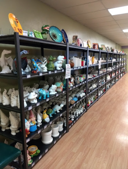 A long aisle of shelves filled with various decorative ceramics and pottery items in a well-lit store.