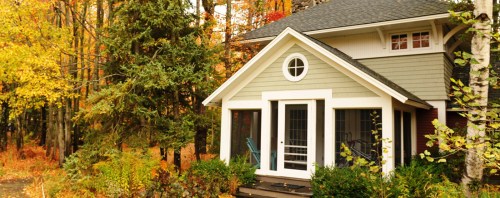 A cozy house surrounded by vibrant autumn foliage and trees, showcasing fall colors in a serene setting.