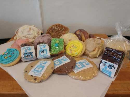 A variety of colorful cookies and treats arranged on a white surface, including decorated cookies and bars.