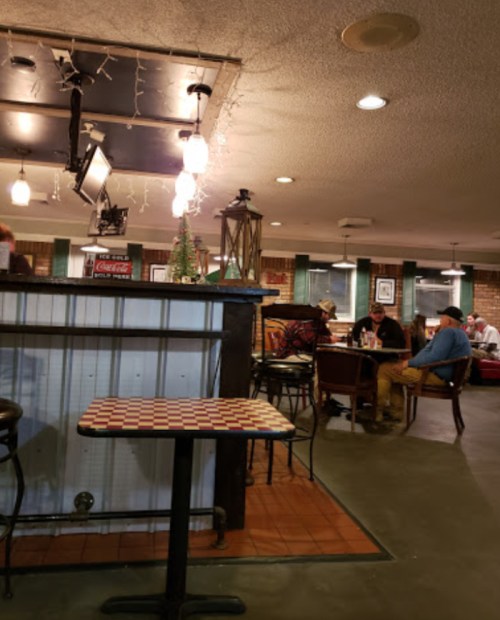 A cozy restaurant interior with tables, chairs, and warm lighting, featuring patrons enjoying their meals.