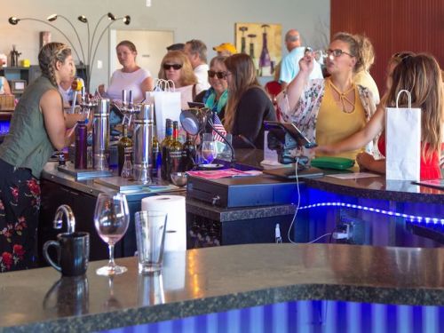 A lively bar scene with people chatting, drinks on the counter, and a mix of casual and stylish attire.