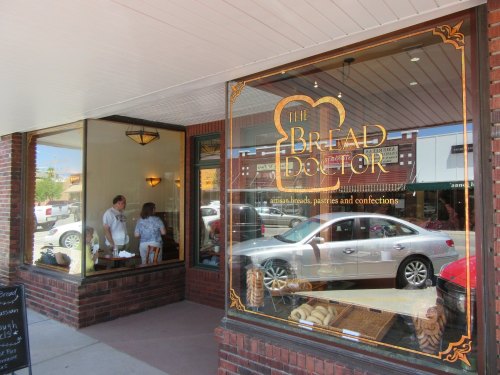 A bakery storefront with a sign reading "The Bread Doctor," showcasing breads and pastries through large windows.