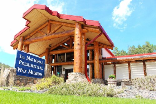 Exterior of the National Presidential Wax Museum, featuring a log cabin-style entrance and a blue sign.