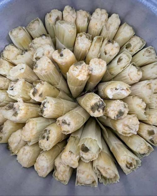 A circular arrangement of tamales wrapped in corn husks, showcasing their golden filling.