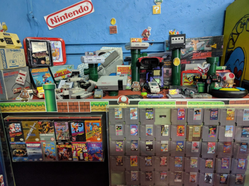 A colorful display of retro Nintendo games, consoles, and memorabilia, featuring iconic characters and game covers.