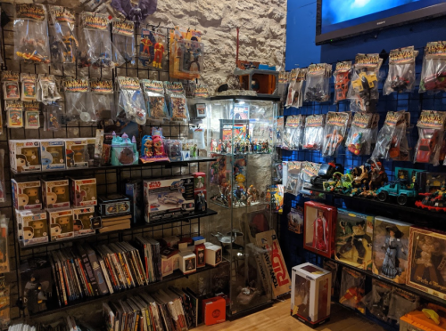 A colorful display of various action figures, collectibles, and toys arranged on shelves and in a glass case.