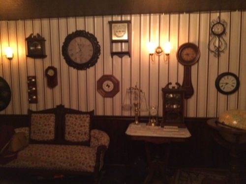 A cozy room with vintage clocks on the wall, a floral couch, and a small table with decorative items.