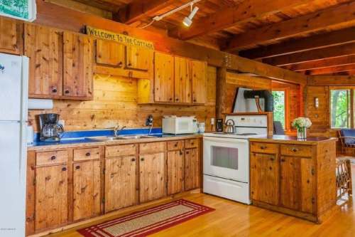Cozy wooden kitchen with blue countertops, white appliances, and a welcoming sign above the cabinets.