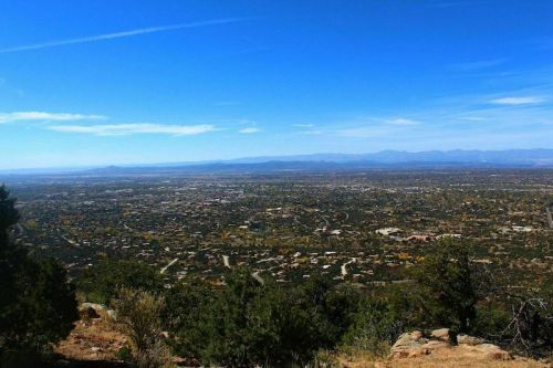 A panoramic view of a sprawling landscape with mountains in the distance under a clear blue sky.