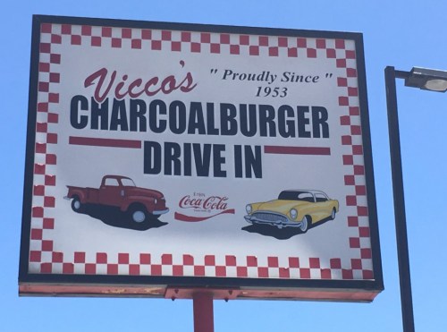 Sign for Vicco's Charcoalburger Drive-In, established in 1953, featuring vintage cars and a Coca-Cola logo.