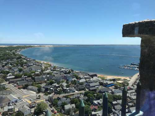 Aerial view of a coastal town with a sandy beach, boats in the water, and clear blue skies.