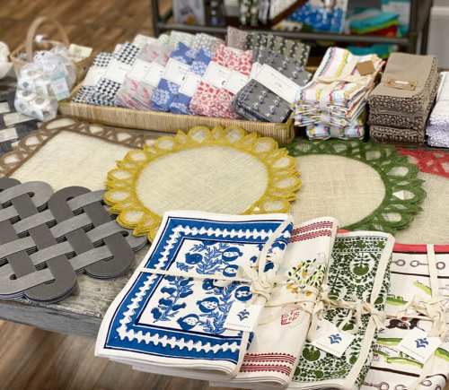 A display of colorful table linens, placemats, and napkins arranged on a wooden table.