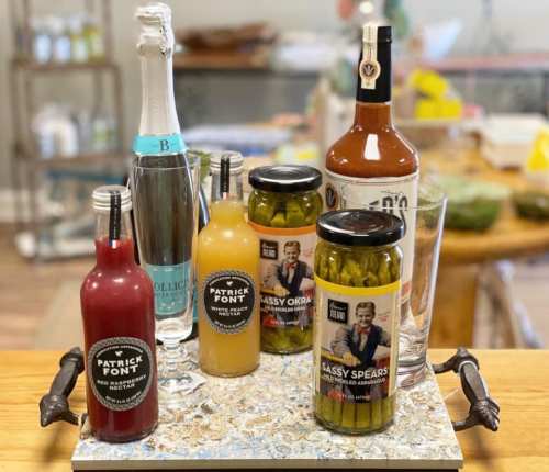 A tray with various beverages, including sparkling water, cocktail mixers, and pickled vegetables.