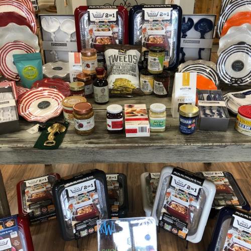 A display of colorful kitchenware, including plates, jars, and cooking accessories, arranged on a wooden table.