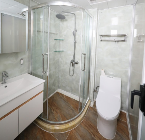 Modern bathroom featuring a glass shower, toilet, and sleek vanity with a sink. Neutral tones and contemporary design.