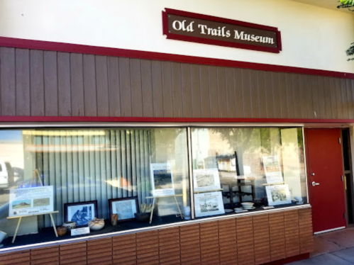 Exterior of the Old Trails Museum, featuring a display window with historical artifacts and information.