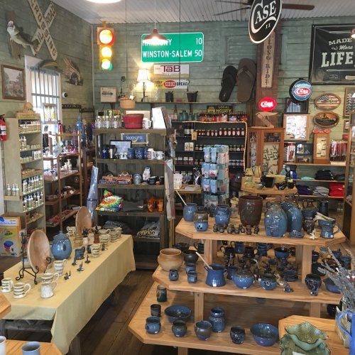 A cozy shop filled with pottery, souvenirs, and vintage signs, showcasing a variety of colorful items on display.
