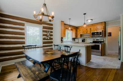 A cozy kitchen with wooden accents, a dining table, and modern appliances, featuring log cabin-style walls.