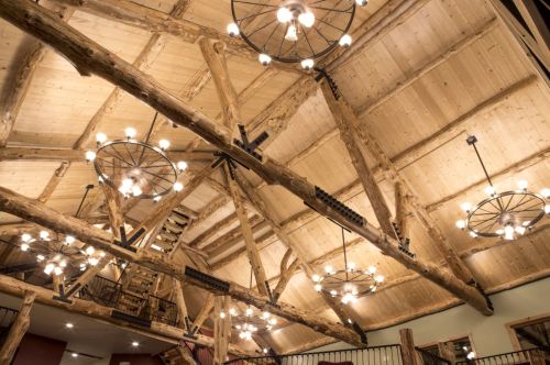 Rustic interior with wooden beams and circular chandeliers, showcasing a warm, inviting atmosphere.