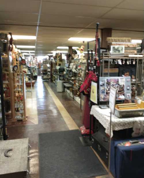 A wide aisle in a vintage store filled with various antiques and collectibles on display.