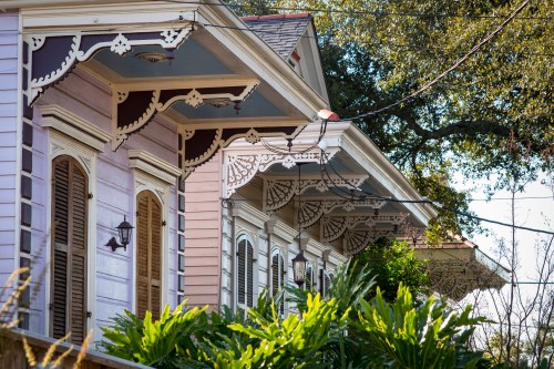 Colorful houses with intricate eaves and lush greenery in a sunny neighborhood.