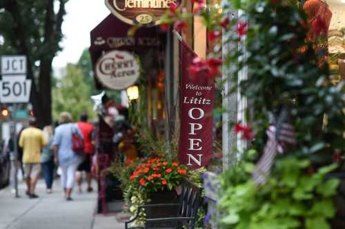 A street scene in Lititz with shops, flowers, and a sign reading "Welcome to Lititz" as people stroll by.