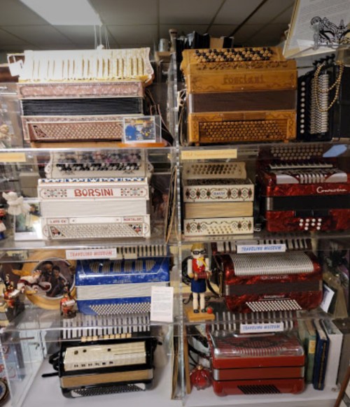A display of various colorful accordions arranged on shelves, showcasing intricate designs and patterns.