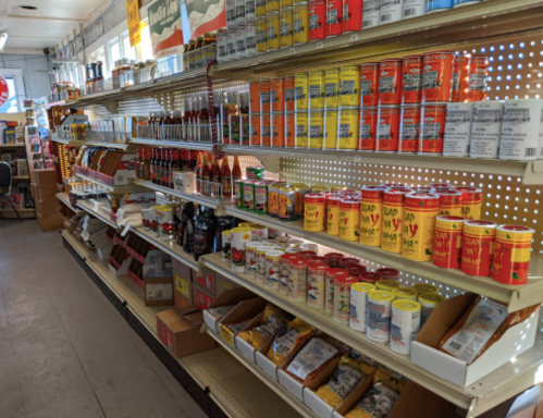 A grocery store aisle filled with various canned goods, sauces, and packaged food items on shelves.