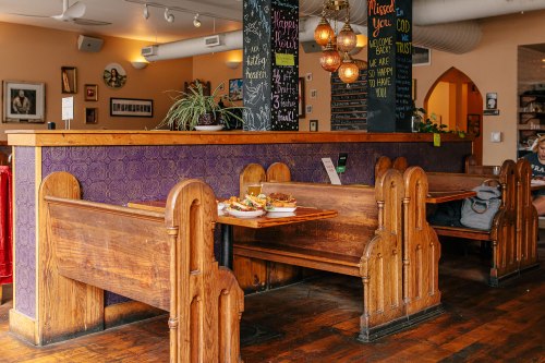 Cozy restaurant interior with wooden booths, colorful decor, and a chalkboard menu in a warm, inviting atmosphere.