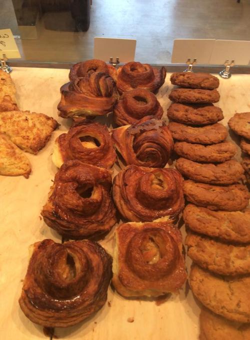 A display of freshly baked pastries, including croissants and cookies, arranged on a wooden surface.
