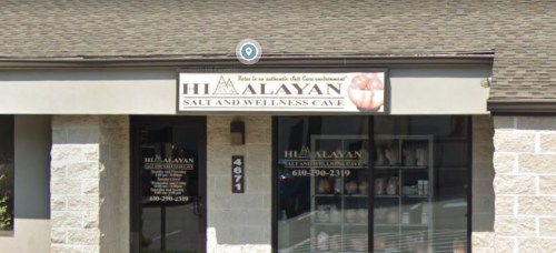 Exterior of Himalayan Salt and Wellness Cave, featuring a sign and large windows, with a stone facade.