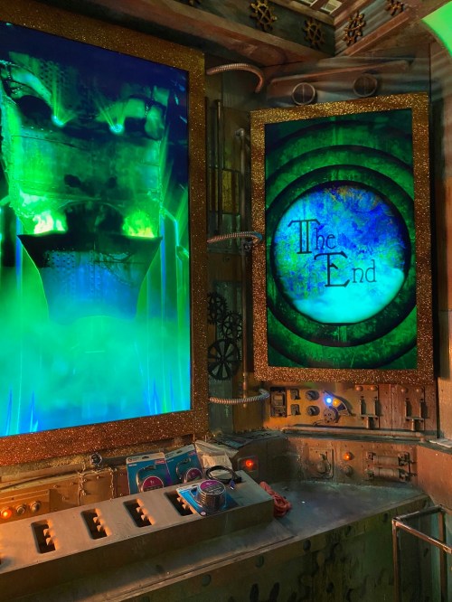 A futuristic control panel with glowing green screens displaying "The End" amidst mechanical elements and fog.