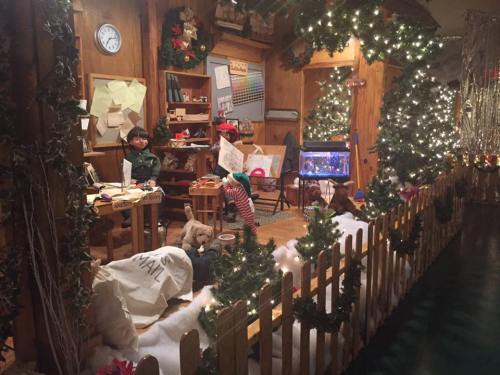 A cozy holiday scene with a decorated room, a fish tank, and festive lights, surrounded by a white snowy landscape.