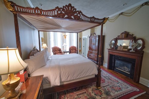 A luxurious bedroom featuring a four-poster bed, elegant furnishings, and a cozy fireplace.