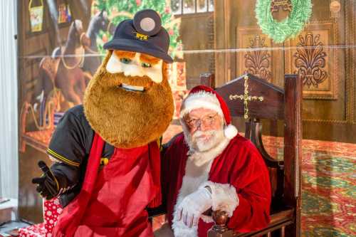 A person in a bear costume and Santa Claus pose together in a festive setting with holiday decorations.