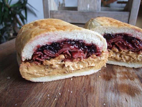 A sandwich cut in half, filled with peanut butter and jelly, showcasing a thick layer of each spread.