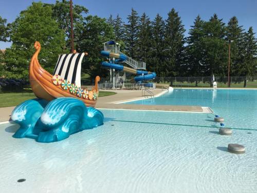 A colorful Viking ship sculpture on a pool deck, with water slides and trees in the background.