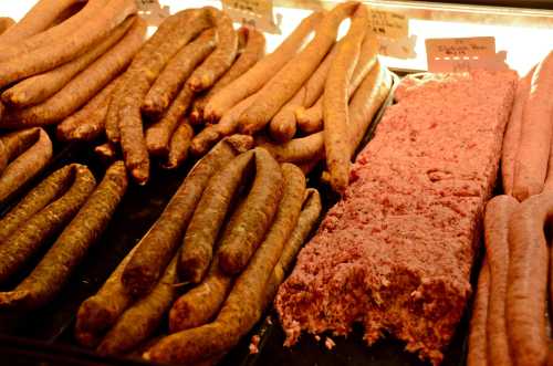 A display of various sausages and a block of ground meat in a butcher shop.