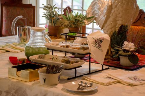 A beautifully set table with desserts, a pitcher, and decorative plants, creating an inviting atmosphere.