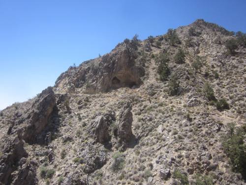 Rocky hillside with sparse vegetation under a clear blue sky.