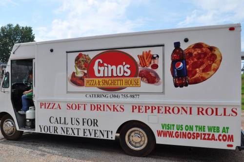 A food truck with "Gino's Pizza & Spaghetti House" signage, offering pizza, soft drinks, and pepperoni rolls.